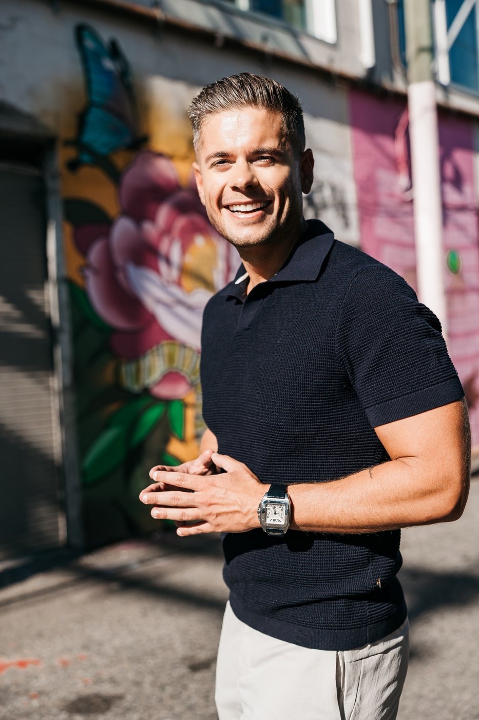 Andrew laughing in a Vancouver alley with a mural behind him