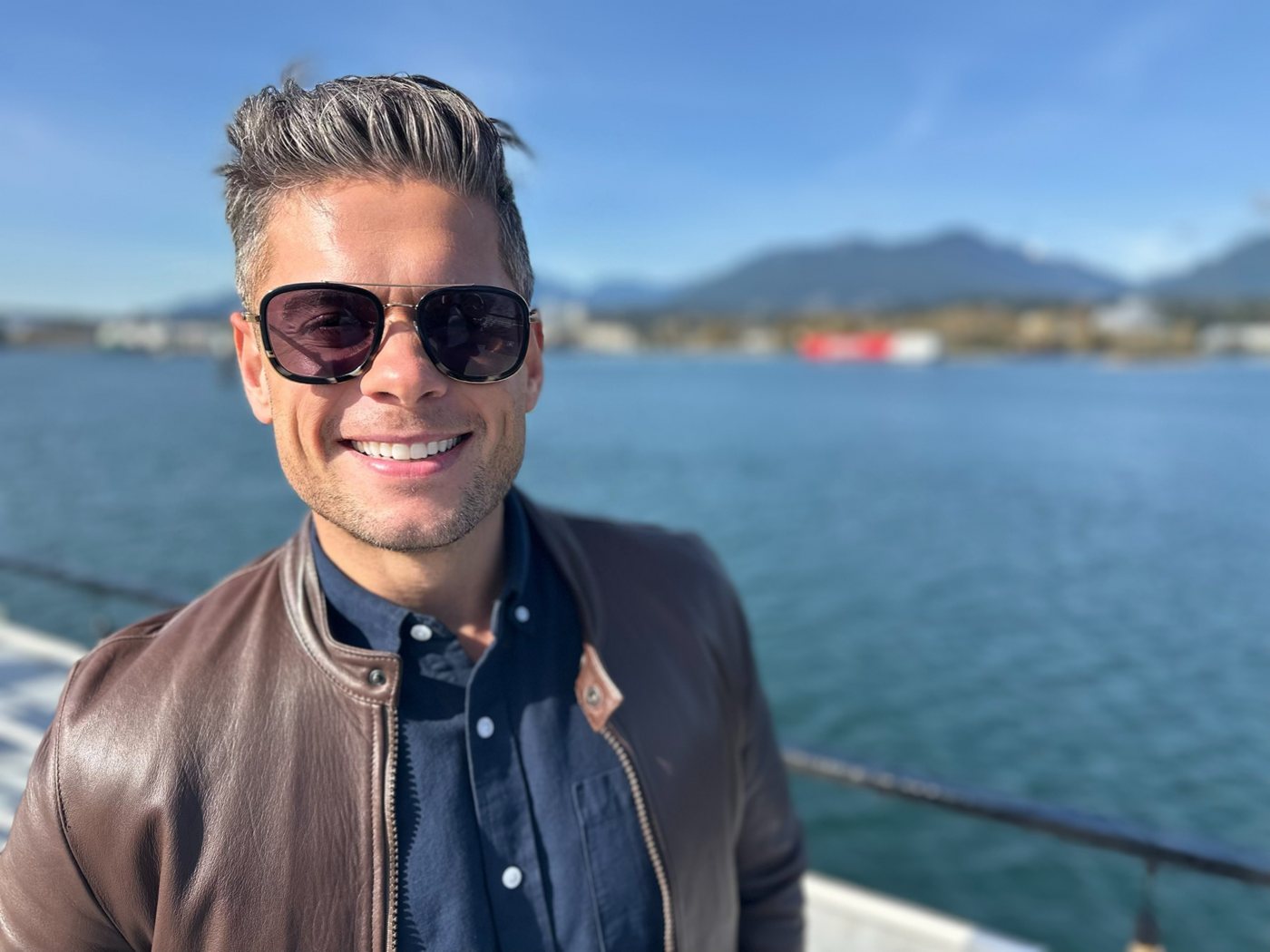 Andrew smiling on the Vancouver waterfront with the North Shore mountains behind